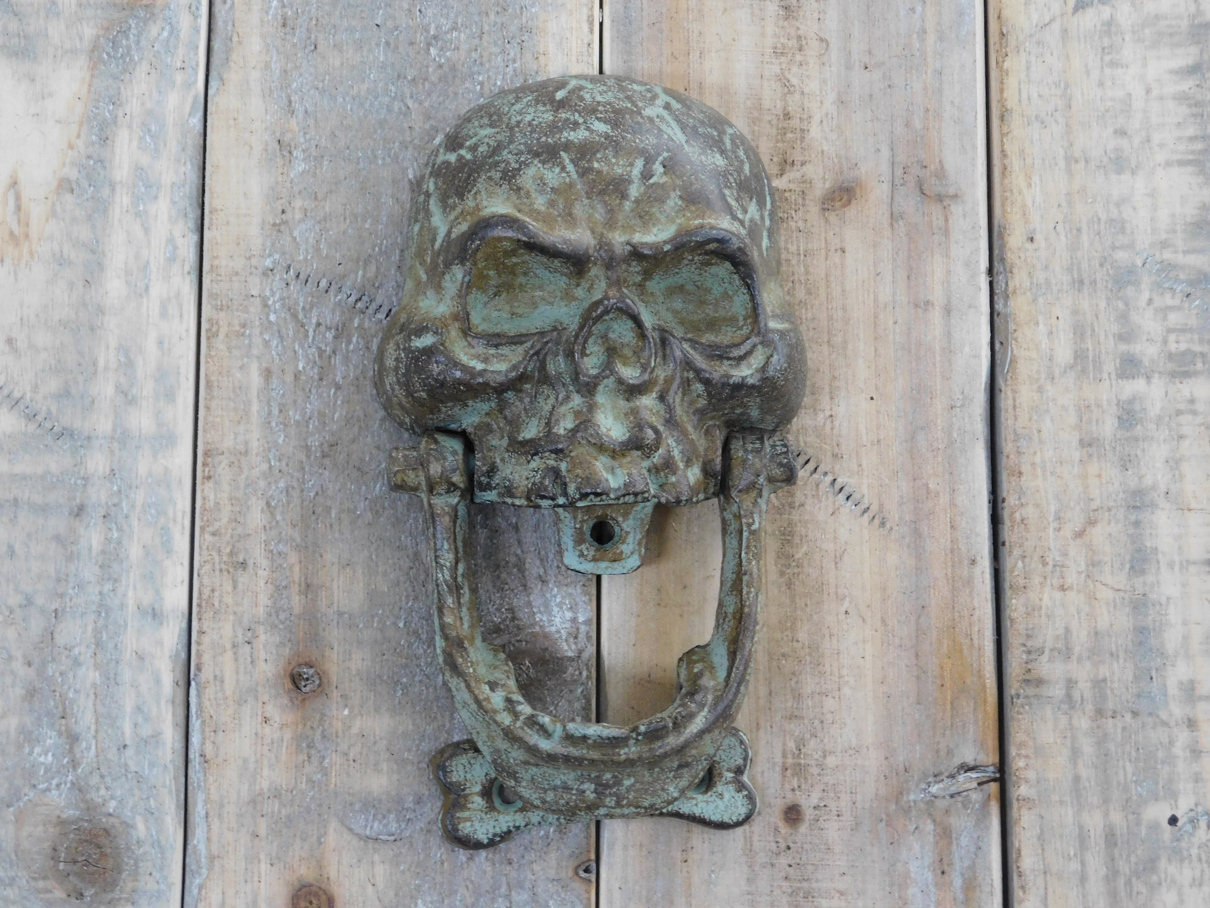 Gietijzeren groen-bruine schedel als deurklopper.