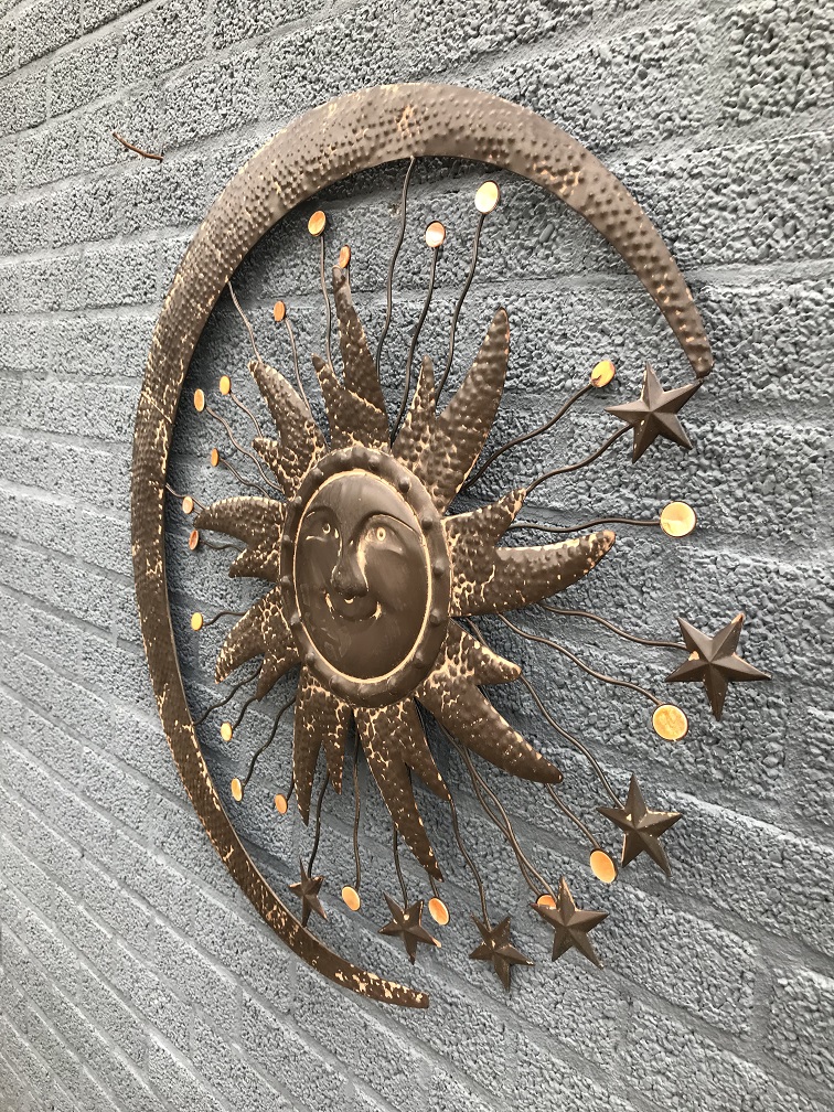 Een metalen wandornament, waarin een zon, een maan en sterren zijn afgebeeld