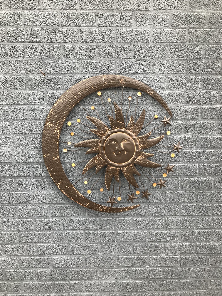 Een metalen wandornament, waarin een zon, een maan en sterren zijn afgebeeld