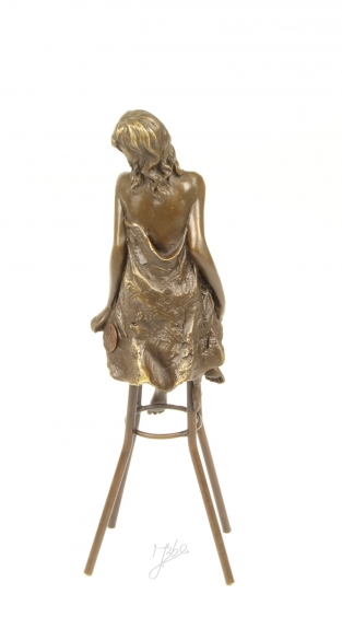 Eine Bronzeskulptur einer barbusigen Dame auf einem Barhocker