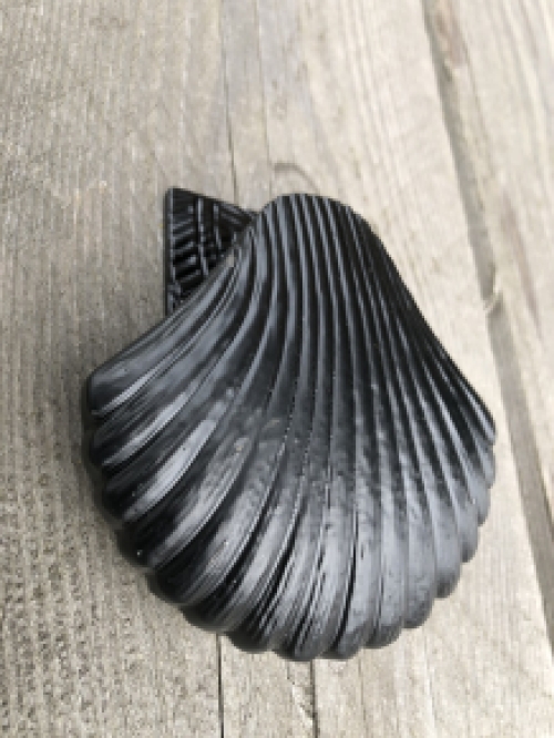 Decoratieve deurklopper in de vorm van een schelp, geheel metaal zwart.