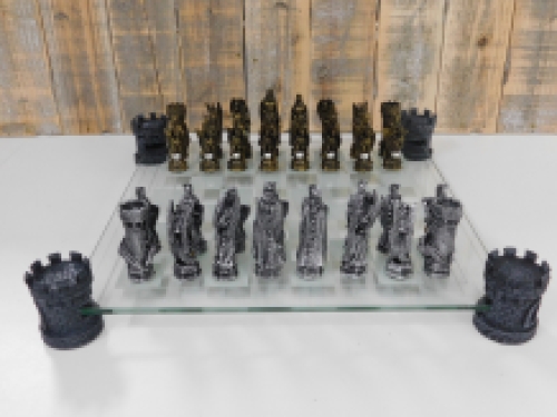 Ein Schachspiel mit dem Thema: ''Ritter-Drachen'', schöne Schachfiguren als mittelalterliche Ritter auf einem Glasschachbrett mit Türmen.
