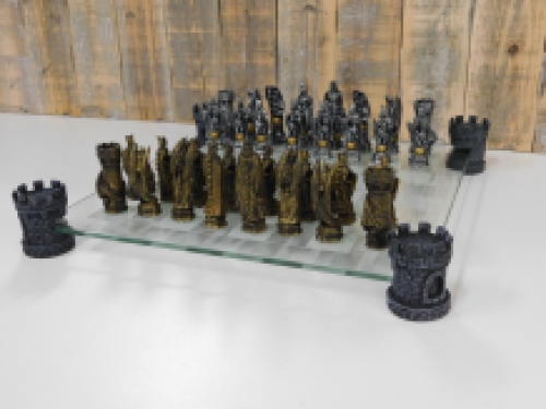 Ein Schachspiel mit dem Thema: ''Ritter-Drachen'', schöne Schachfiguren als mittelalterliche Ritter auf einem Glasschachbrett mit Türmen.