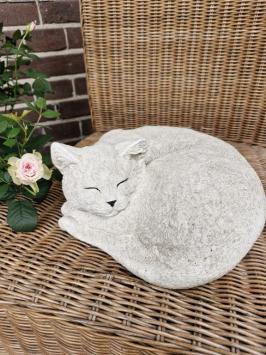 Zusammengekauerte, lebensecht wirkende Katze, Beton