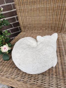 Zusammengekauerte, lebensecht wirkende Katze, Beton