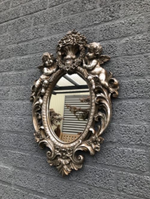 Ein feiner dekorativer Spiegel, silbern umrahmt mit einem Kranz, der von 2 Engeln getragen wird
