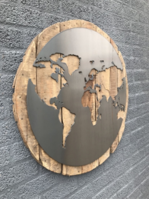 Ein großes Wandornament aus Holz mit einer Welt darauf, ein Meer aus Metall