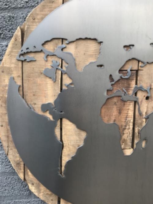 Ein großes Wandornament aus Holz mit einer Welt darauf, ein Meer aus Metall