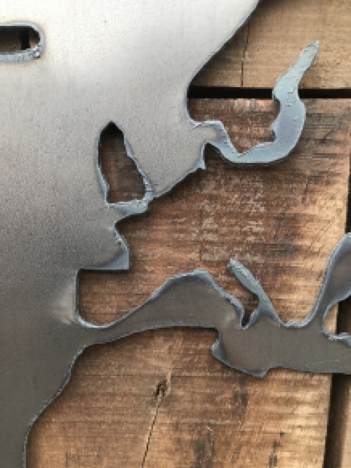Ein großes Wandornament aus Holz mit einer Welt darauf, ein Meer aus Metall