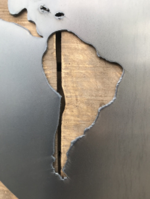Ein großes Wandornament aus Holz mit einer Welt darauf, ein Meer aus Metall