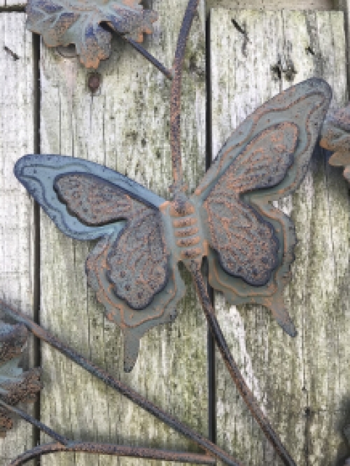 Een metalen wandornament met bladeren en vlinders, zeer decoratief!